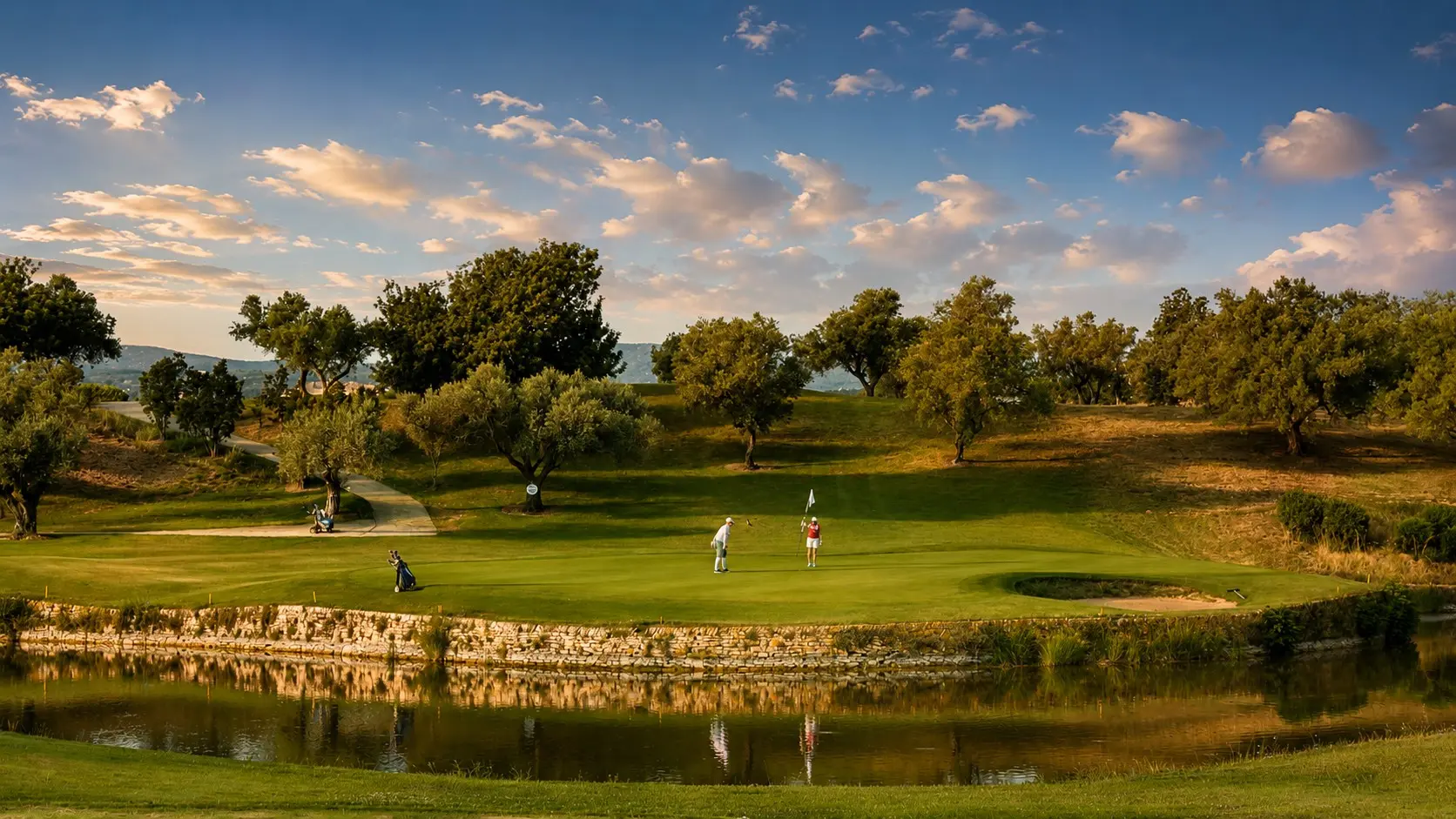 El campo de Panorámica Golf entre olivos y agua, con las montañas al fondo